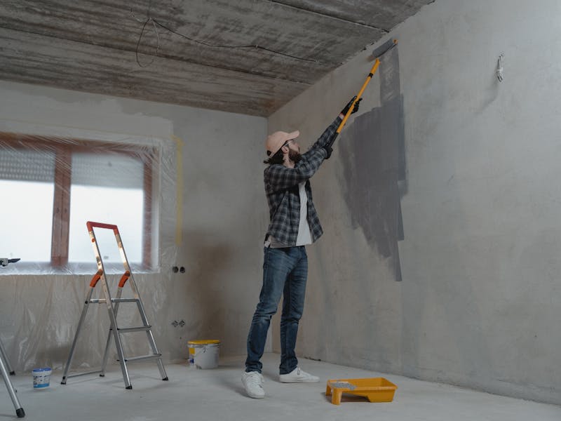 Painter rolling fresh paint on a repaired wall